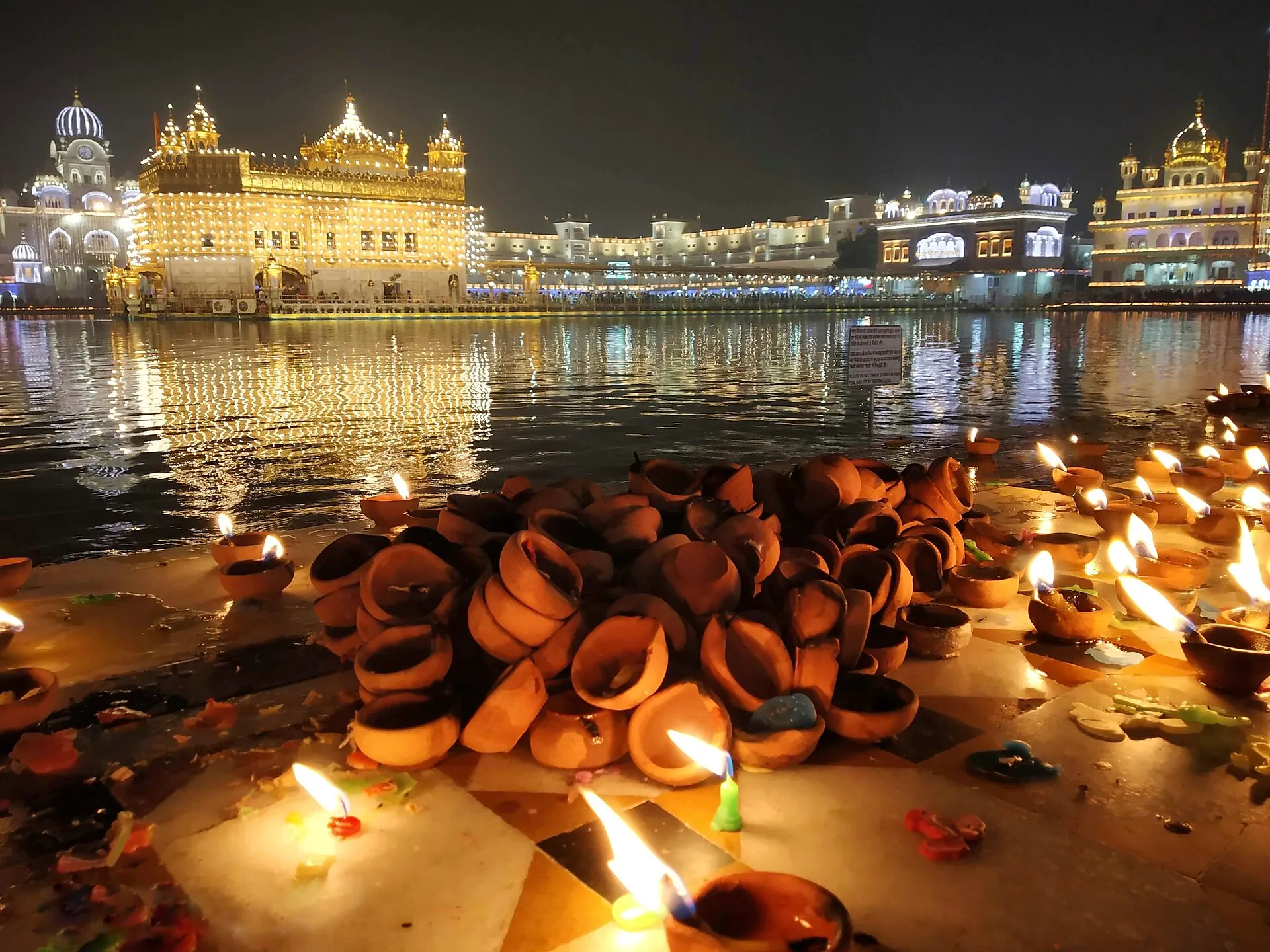 Golden Temple illuminated at night during Diwali, diyas burning at the edge of the sarovar