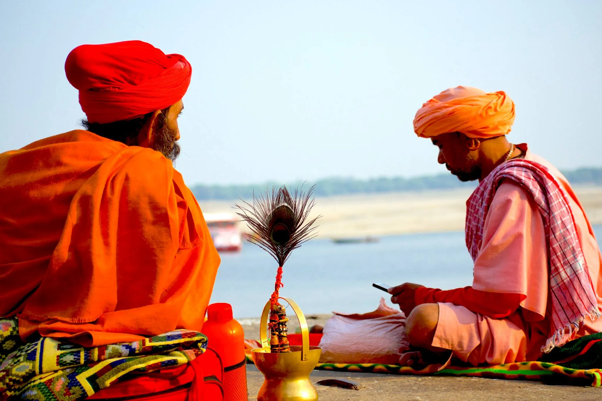 Two orange-robed sadhus seated by the Ganga river at Varanasi