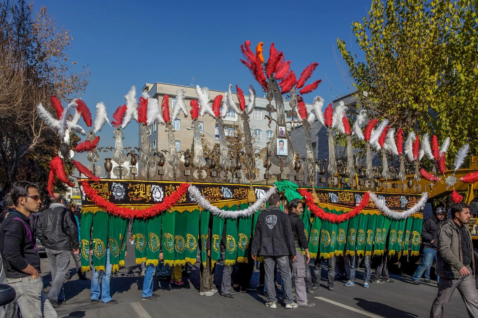 Mourners carrying a large decorated alam standard in an Ashura procession