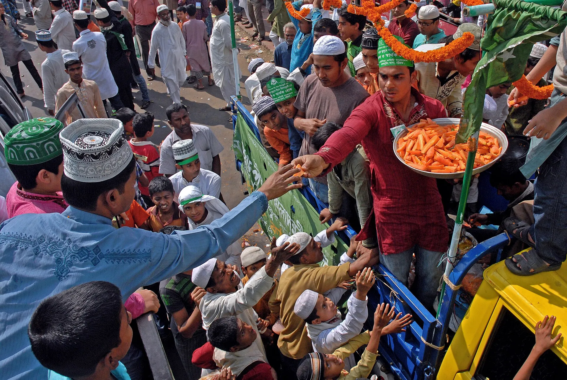 Crowds at a Milad-un-Nabi procession as sweets are distributed from a decorated truck