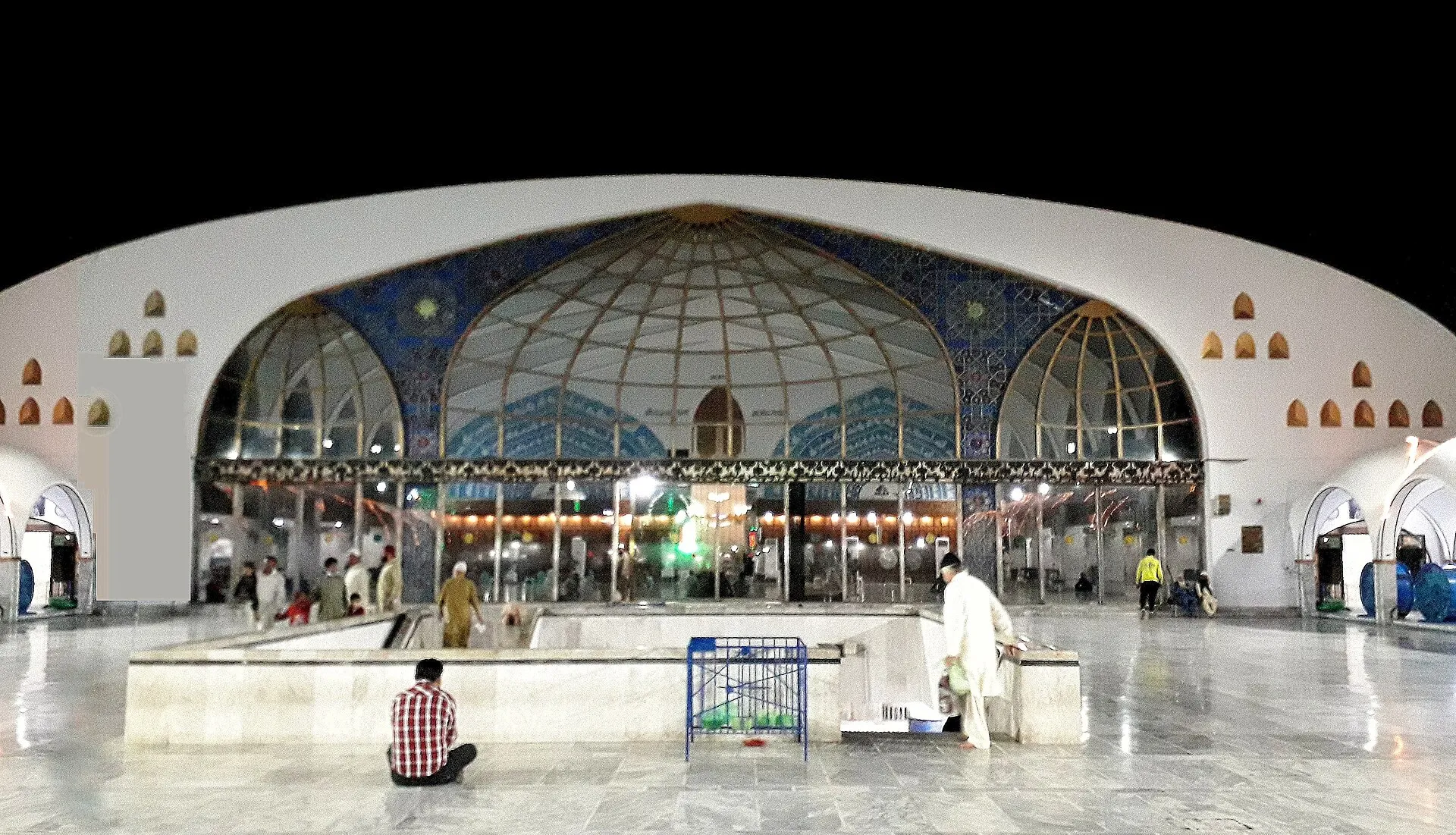 The illuminated glass domed hall of the Data Darbar shrine in Lahore at night