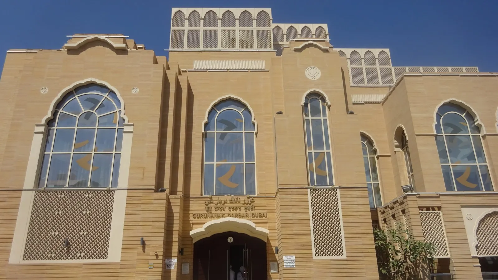 The Guru Nanak Darbar gurdwara in Jebel Ali, Dubai, its sand coloured facade with tall arched windows and the Khanda above the entrance